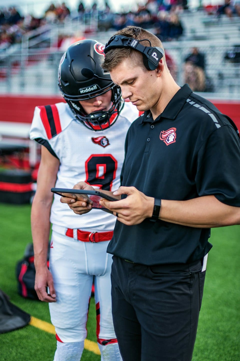 Allenatore e giocatore esaminano la strategia su un tablet durante una partita.