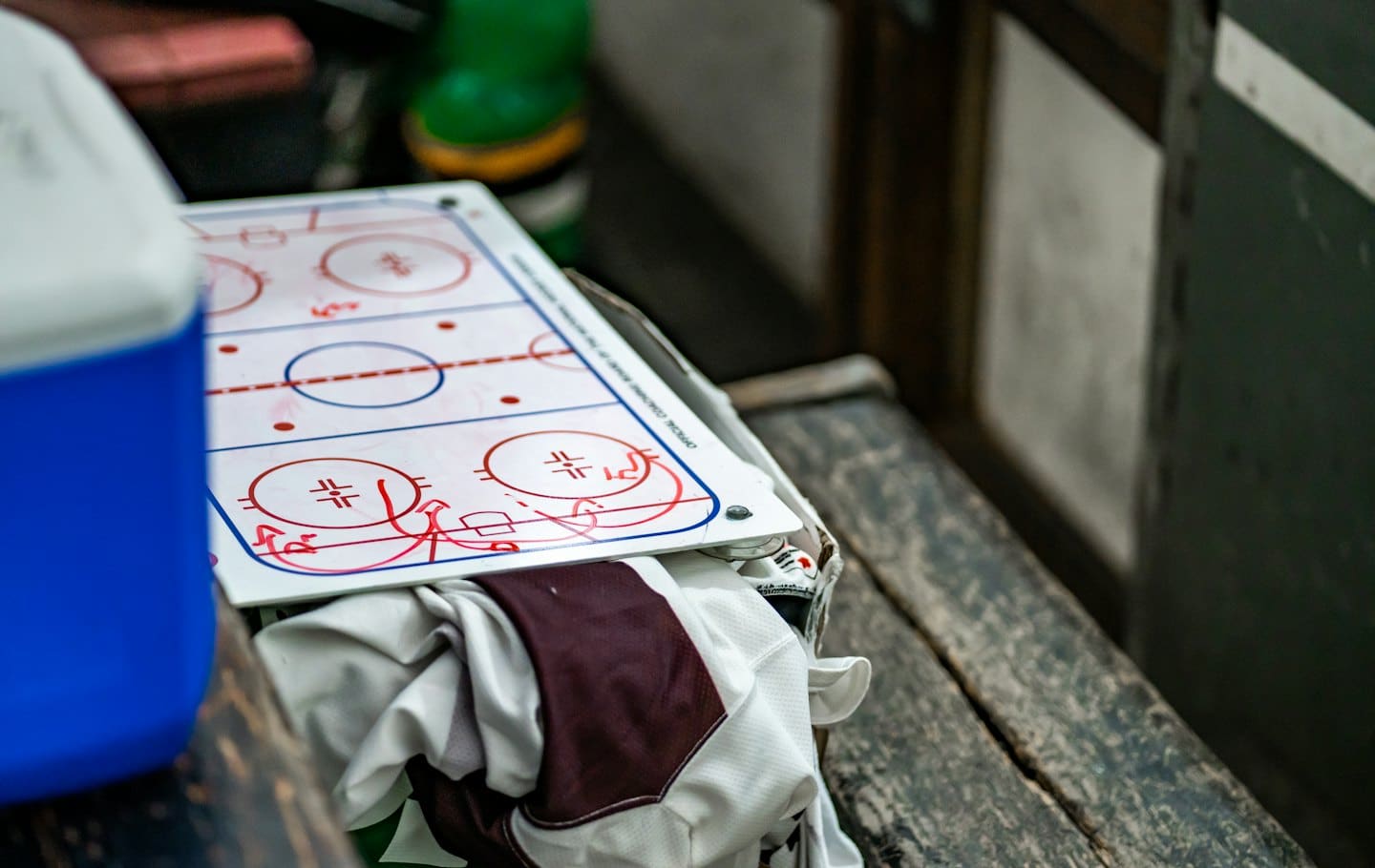 Lavagna tattica di un allenatore di hockey con diagrammi su una panchina di legno.