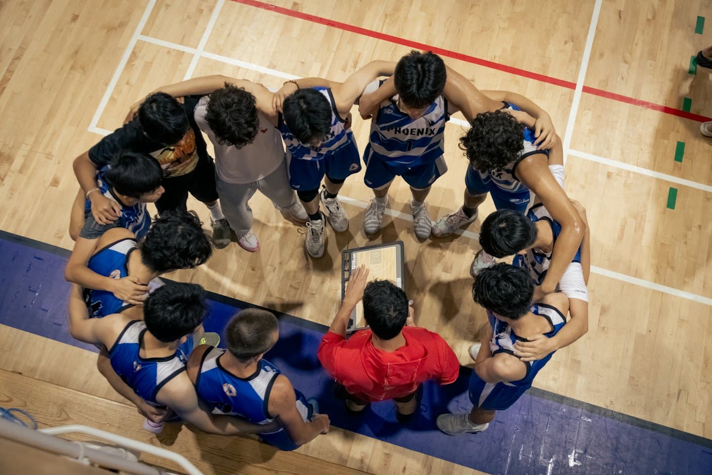 Un allenatore di basket spiega la strategia alla sua squadra in campo.