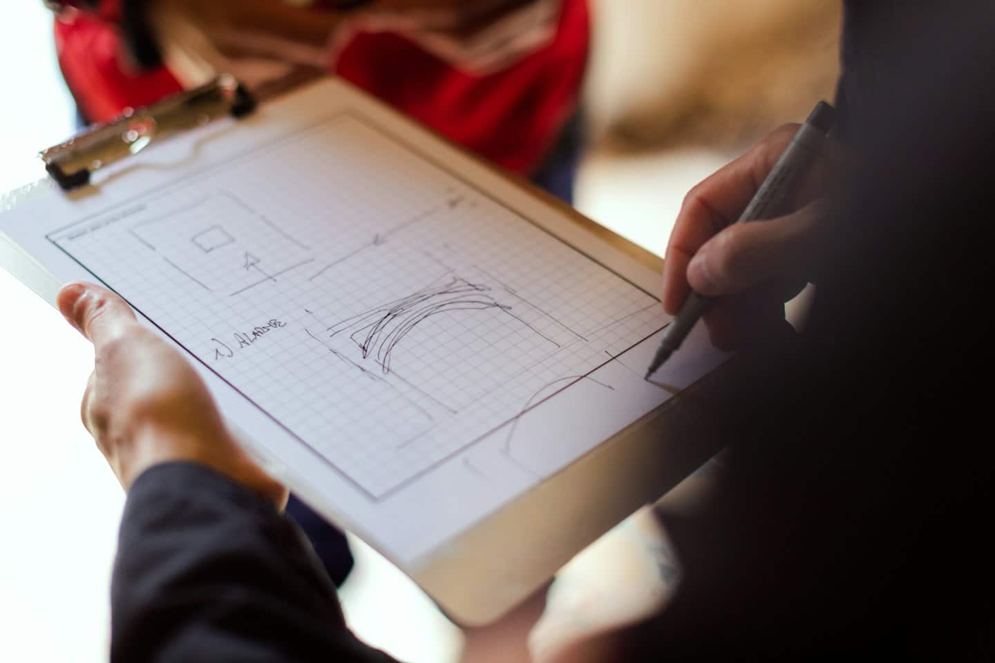 Due persone collaborano a uno schizzo tecnico con una clipboard.